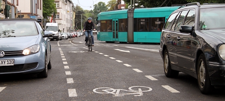 Radfahrer auf markiertem Radweg zwischen zwei Autospuren