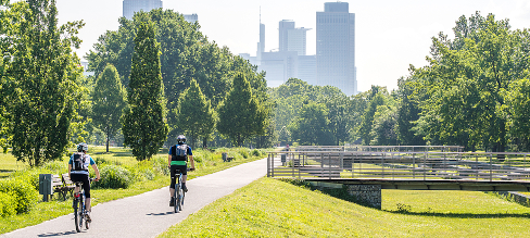 Radfahrende in Parklandschaft vor der Frankfurter Skyline